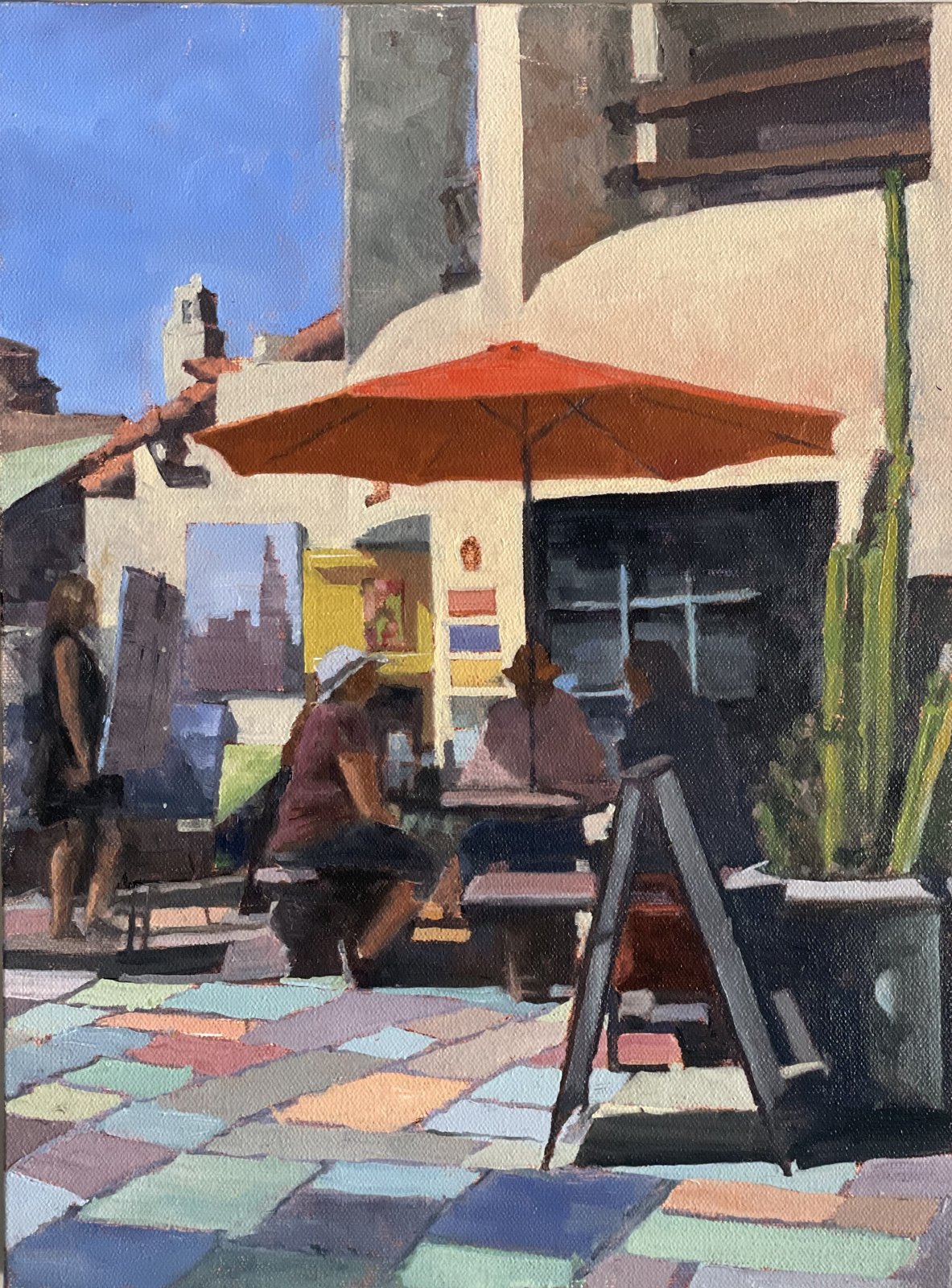 Painting of people at cafe tables under an orange umbrella in the Spanish Village at Balboa Park